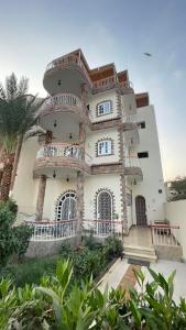 a large white building with balconies and a palm tree at Full Moon House in Luxor