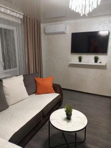 uma sala de estar com um sofá e uma mesa em Квартира в центре с гостиничным сервисом. em Petropavl