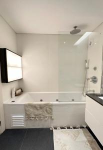 uma casa de banho branca com uma banheira e um lavatório em Groovy Caparica Gem with Large Sunny Terrace em Costa da Caparica