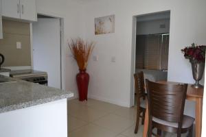 eine Küche mit einem Tisch und Stühlen und einer Vase mit Blumen in der Unterkunft Bryanston Elgin - Cottage 5 in Johannesburg