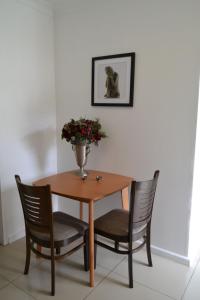einen Holztisch mit zwei Stühlen und eine Vase mit Blumen in der Unterkunft Bryanston Elgin - Cottage 5 in Johannesburg