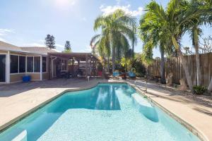 a swimming pool in front of a house with palm trees at Tropical Island Escape Near Disney, Beach, Cruise in Merritt Island