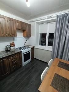 uma cozinha com armários de madeira, uma mesa e um fogão em Квартира в центре с гостиничным сервисом. em Petropavl