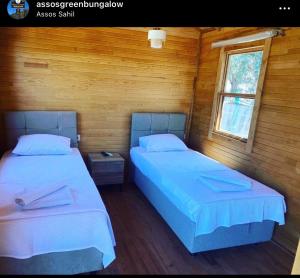 2 camas en una habitación con paredes de madera en Assos Green Bungalow, en Ayvacık