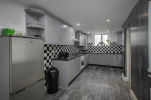 a kitchen with white cabinets and a black and white tile wall at Lovely Home in Blackpool For You in Blackpool