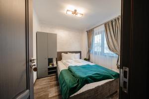 um quarto com uma cama com lençóis verdes e uma janela em Casa Diana em Vatra Dornei