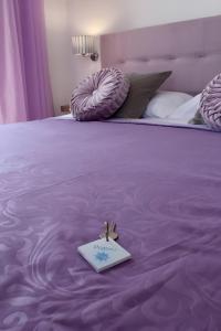 Una cama morada con una nota encima. en Antares Rooms en Castellabate
