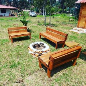 three wooden benches in a field with a fire pit at Cabaña campestre #1 in Ráquira