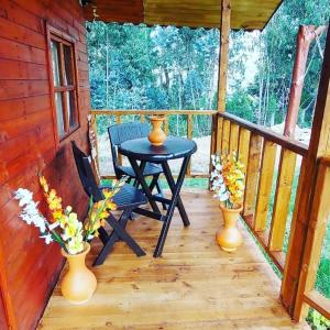une terrasse couverte en bois avec une table et des vases. dans l'établissement Cabaña campestre #1, à Ráquira