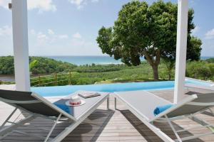 un patio con 2 sedie, un tavolo e una piscina di THE VIEW - Magnifique Villa face à la Mer a Sainte-Anne