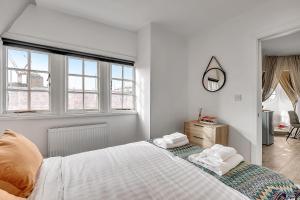 Un dormitorio blanco con una cama con toallas. en The Phillimore en Londres