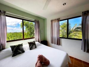 a bedroom with two beds and two large windows at Sirenas Caribbean Rooms Holbox in Holbox Island