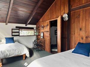 a bedroom with two beds and wooden walls at Casa Cantera in Teziutlán