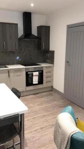 a kitchen with a stove top oven next to a table at Lovely 2-Bed Apartment in Stanford-le-Hope in Stanford-le-Hope