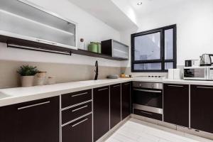 eine Küche mit dunkelbraunen Schränken und einem Fenster in der Unterkunft 2Bedroom Suite with Balcony Shenkin Hotel in Tel Aviv