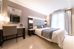 a bedroom with a bed and a desk and a television at Hotel Europa in Pamplona