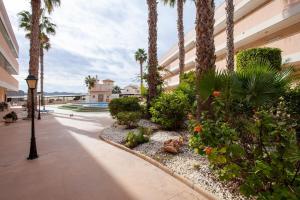 un patio con palmeras, una luz de la calle y un edificio en APARTAMENTO EL PALMERAL LOS NIETOS CERCA DE LA MANGA en Los Nietos