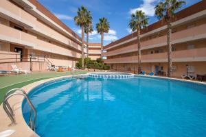 una piscina frente a un edificio con palmeras en APARTAMENTO EL PALMERAL LOS NIETOS CERCA DE LA MANGA, en Los Nietos