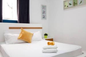 Schlafzimmer mit einem Bett mit weißer Bettwäsche und gelben Kissen in der Unterkunft 2Bedroom Suite with Balcony Shenkin Hotel in Tel Aviv