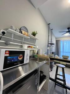 eine Küche mit einer Spüle und einer Mikrowelle in der Unterkunft Cozy Sky Trees Bukit Indah Netflix and Amenities B06 in Johor Bahru