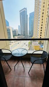 d'un balcon avec deux chaises, une table et une fenêtre. dans l'établissement The Sand Castle - Bahar 6, The Walk at JBR, Near JBR Tram Station, à Dubaï