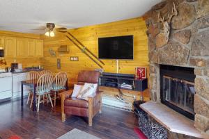a living room with a stone fireplace and a television at Silver Creek - Door 418 in Granby