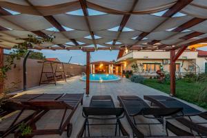 eine Terrasse mit Tischen und Stühlen und einem Pool in der Unterkunft Villa Marijana, rural,private pool,playground in Gorica