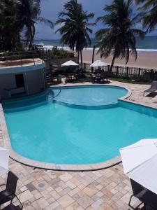 a large blue swimming pool next to a beach at Pousada Caravelas de Pinzón in Cabo de Santo Agostinho