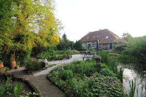 een tuin voor een huis met een vijver bij Karin's kruidenhoeve B&B kamer Kamille met Finse sauna in Lutten