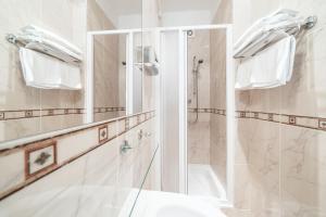 a white bathroom with a shower and a sink at Hotel Raffaello Prague in Prague