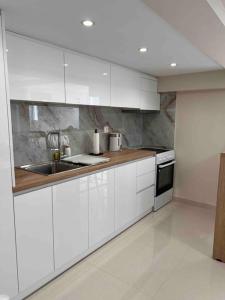 eine Küche mit weißen Schränken und einem Waschbecken in der Unterkunft Minimal Cozy Apartment in Mytilini