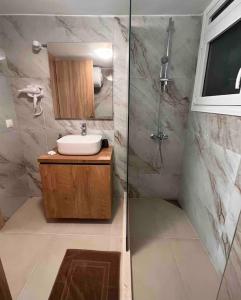 a bathroom with a sink and a shower with a mirror at Minimal Cozy Apartment in Mytilene