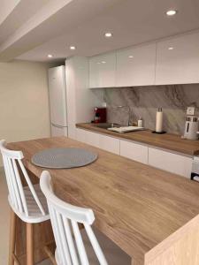 eine Küche mit einem Holztisch und weißen Schränken in der Unterkunft Minimal Cozy Apartment in Mytilini