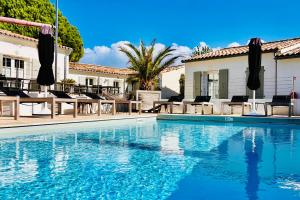 a swimming pool in front of a house at Hotel Les Bois Flottais in Le Bois-Plage-en-Ré