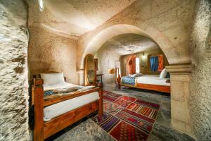 um quarto com 2 camas num quarto de pedra em Caverna Hotel Premium Caves em Goreme