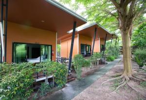 ein orangefarbenes Gebäude mit Bänken und einem Baum in der Unterkunft Plawan lipe Bungalows in Ko Lipe