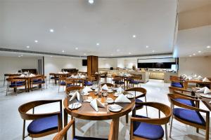 um restaurante com mesas e cadeiras de madeira e um bar em The Fern Residency, Subhash Bridge, Ahmedabad em Ahmedabad