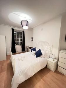 a bedroom with a large white bed with blue pillows at Lovely 2 bed flat in SOHO! in London