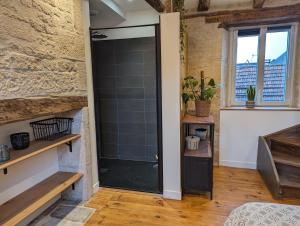 a glass shower door in a room with a brick wall at Maison de Bourg Cressensac in Cressensac +5 photos