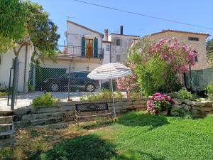 a bench with an umbrella in front of a house at Appartamento Augusta - Residenza la Madonina in Morciano di Romagna