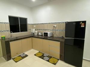 cocina con nevera negra y microondas en Shaleishah Homestey, en Kuantan