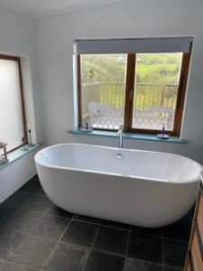 baño con una gran bañera blanca y ventana en The Fuschias en Camp