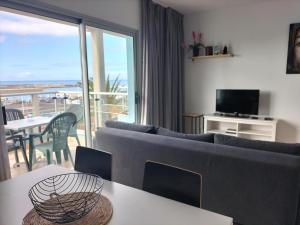 a living room with a couch and a table with a television at Residencial Jandía Marina in Morro del Jable