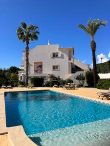 a swimming pool in front of a house with palm trees at Apartamento Jacadi in Ferragudo