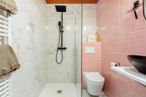 uma casa de banho cor-de-rosa com um chuveiro e um WC. em Le Studio du Perron em Liège