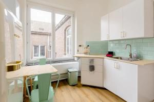 een keuken met witte kasten en een tafel en stoelen bij Le Studio en Feronstrée in Luik
