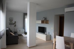 a white living room with a couch and a tv at AR Apartamentos in Soto Real