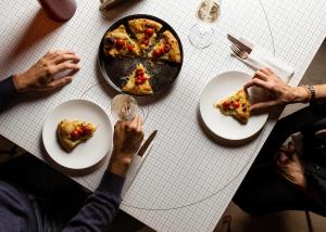 a group of people sitting at a table eating pizza at Hotel Royal Continental in Naples