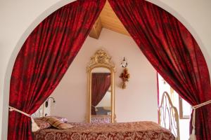 a bedroom with red curtains and a mirror at Appartamento Augusta - Residenza la Madonina in Morciano di Romagna
