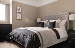 a bedroom with a large bed with white and black pillows at The Leicester Square Apartment By Hok Living in London